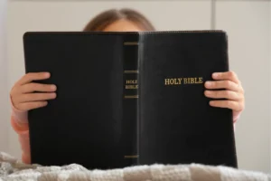 A child holding a Holy Bible, representing the importance of Christian parenting tips in nurturing godly children and prioritizing spiritual education.