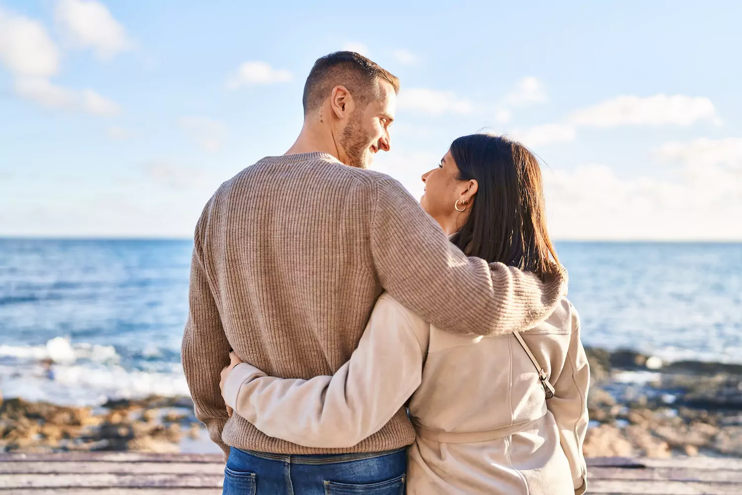 A couple stands arm-in-arm on a beach with the water in the background. They are gazing into each other's eyes. The stresses of everyday life can tax your marriage. Here are 12 suggestions to cultivate a deeper friendship with your spouse.