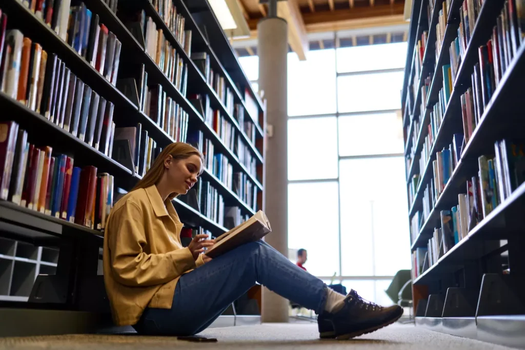 An introverted woman sits in a nice quiet place in a library among stacks of books. If you married an introvert, here are five strategies to help you appreciate your differences and leverage them to build a stronger marriage.