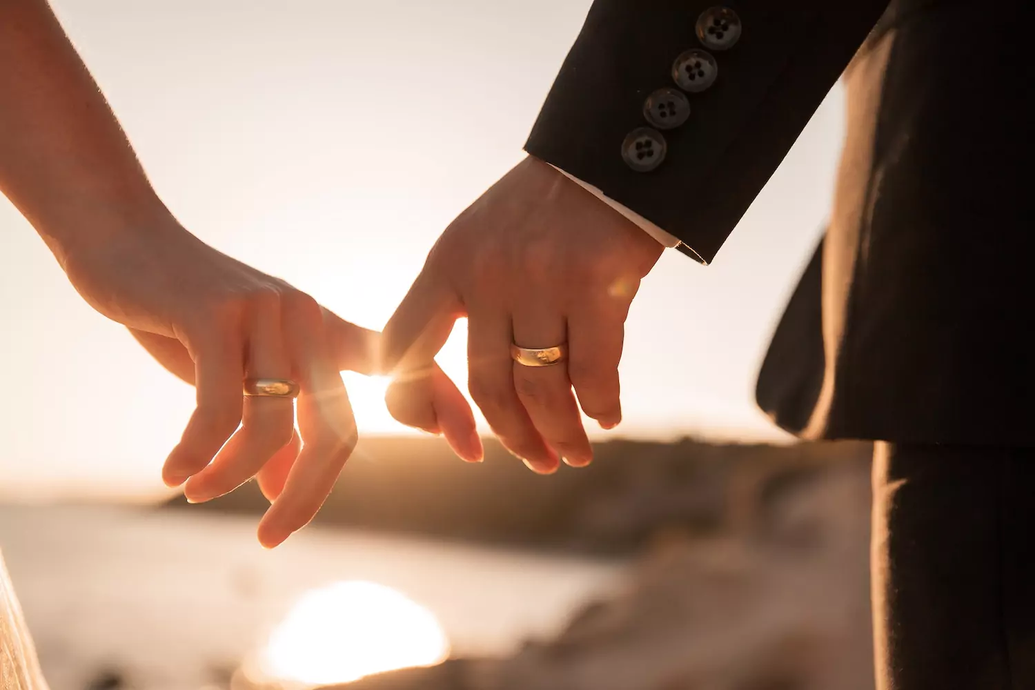 A close-up of a married couple holding hands as they walk together in a sunset. They are both wearing large, prominent wedding rings. You can do little things to make your marriage happier. We hope these stories will give you ideas for a happier marriage.