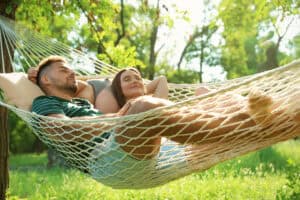 Young couple resting in comfortable hammock at green garden.