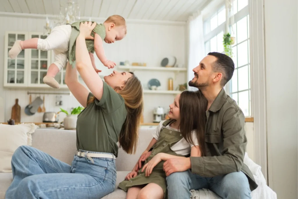 Couple playing with their baby, with their little girl watching