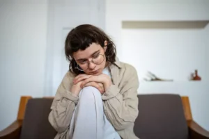 Sad teen, sitting on the couch, contemplating the deconstruction of her faith