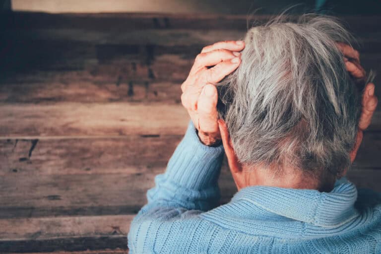 A sad elderly woman holding her head in her hands