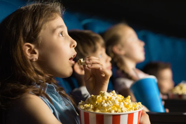 Little girl watching Wicked Part 1 eating popcorn she is mesmerized.