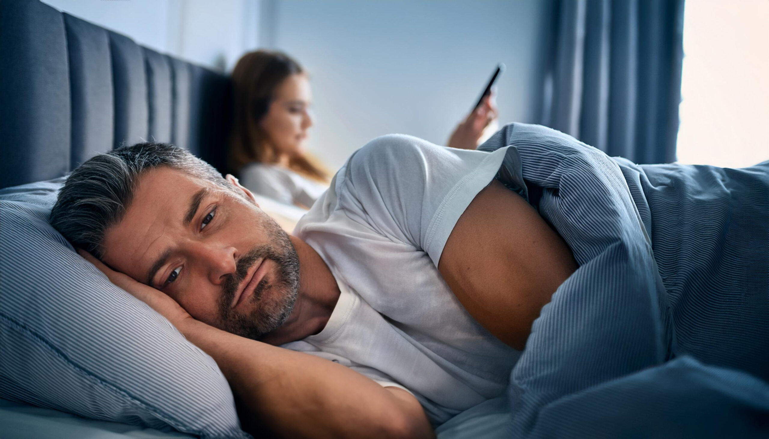 A man fights loneliness while his wife looks at her smartphone.