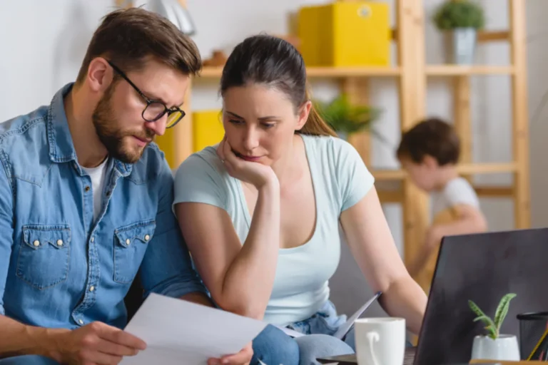 Worried couple sitting at the table looking over bills