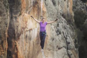 A woman is walking along a tightrope in nature.