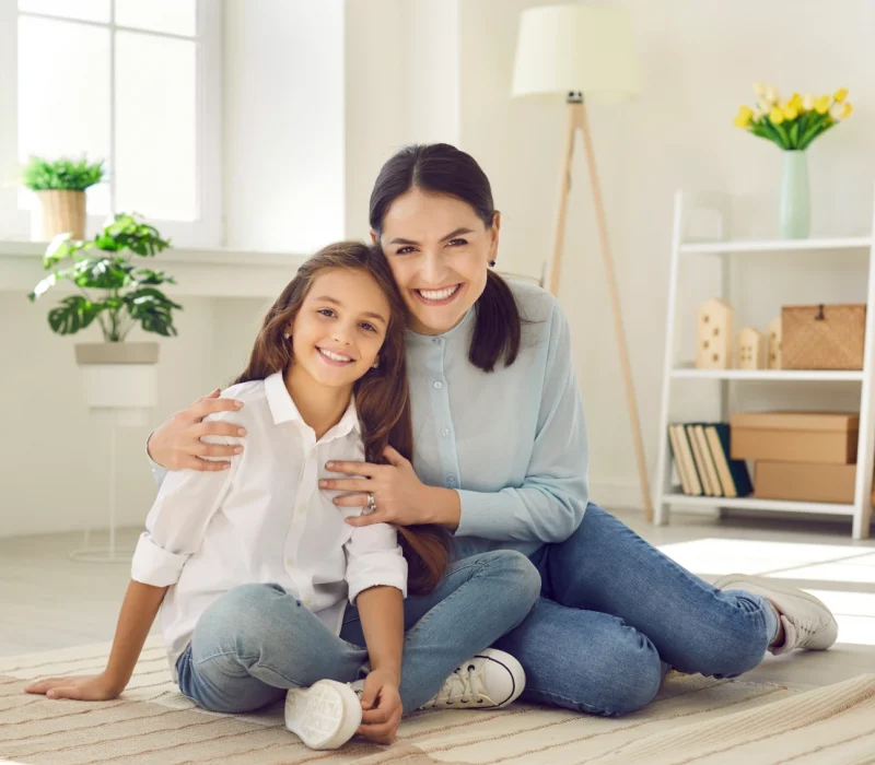 Smiling mother & young daughter sitting on the floor